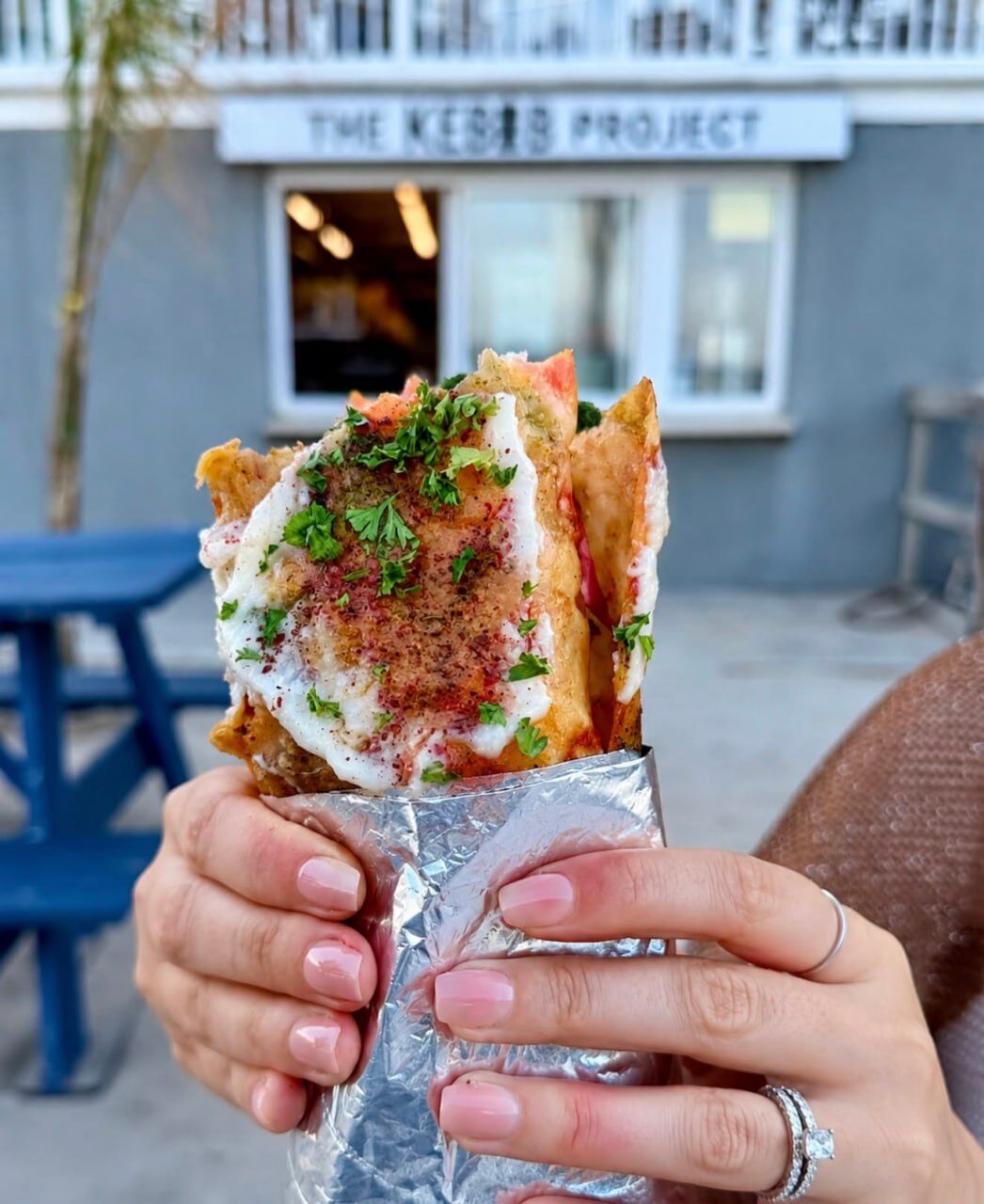 Loaded pita wrap held in front of The Kebob Project